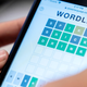 A smartphone screen displays the Worldle game on its screen.